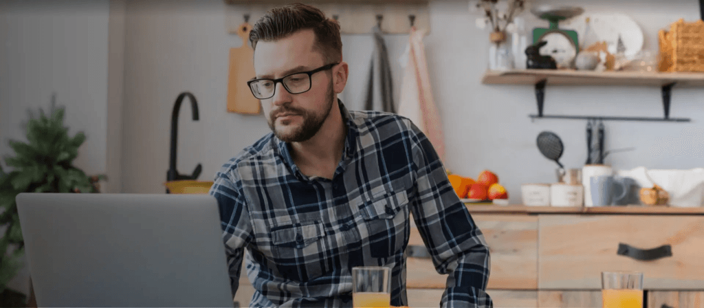 Man using laptop in comfort of home in a remote work setting without implementation of futuristic buildings
