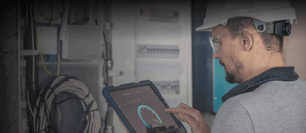 Technician working on a switchboard using a tablet with IoT predictive maintenance system