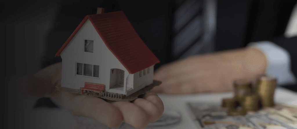 Picture with a house miniature and coins representing property management.