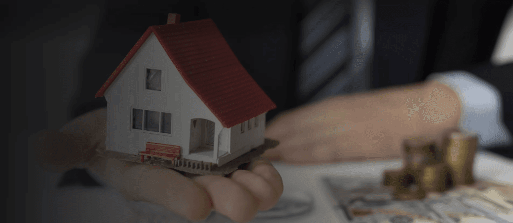 Picture with a house miniature and coins representing property management.