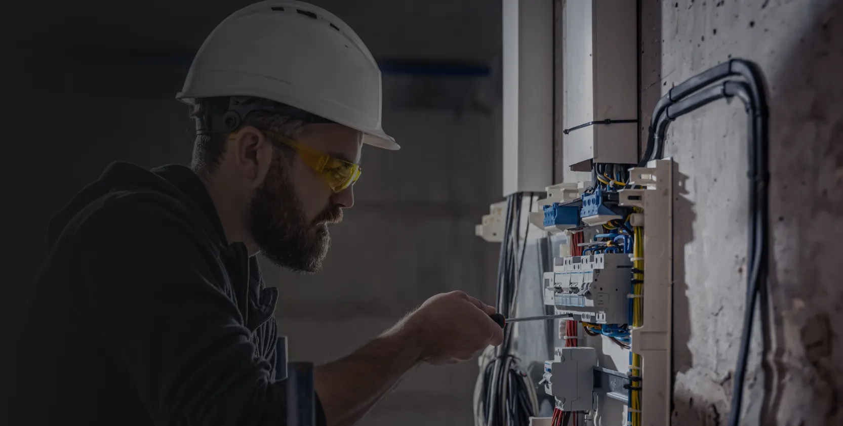 Facility maintenance is under process by a technician as he repairs the switchboard.