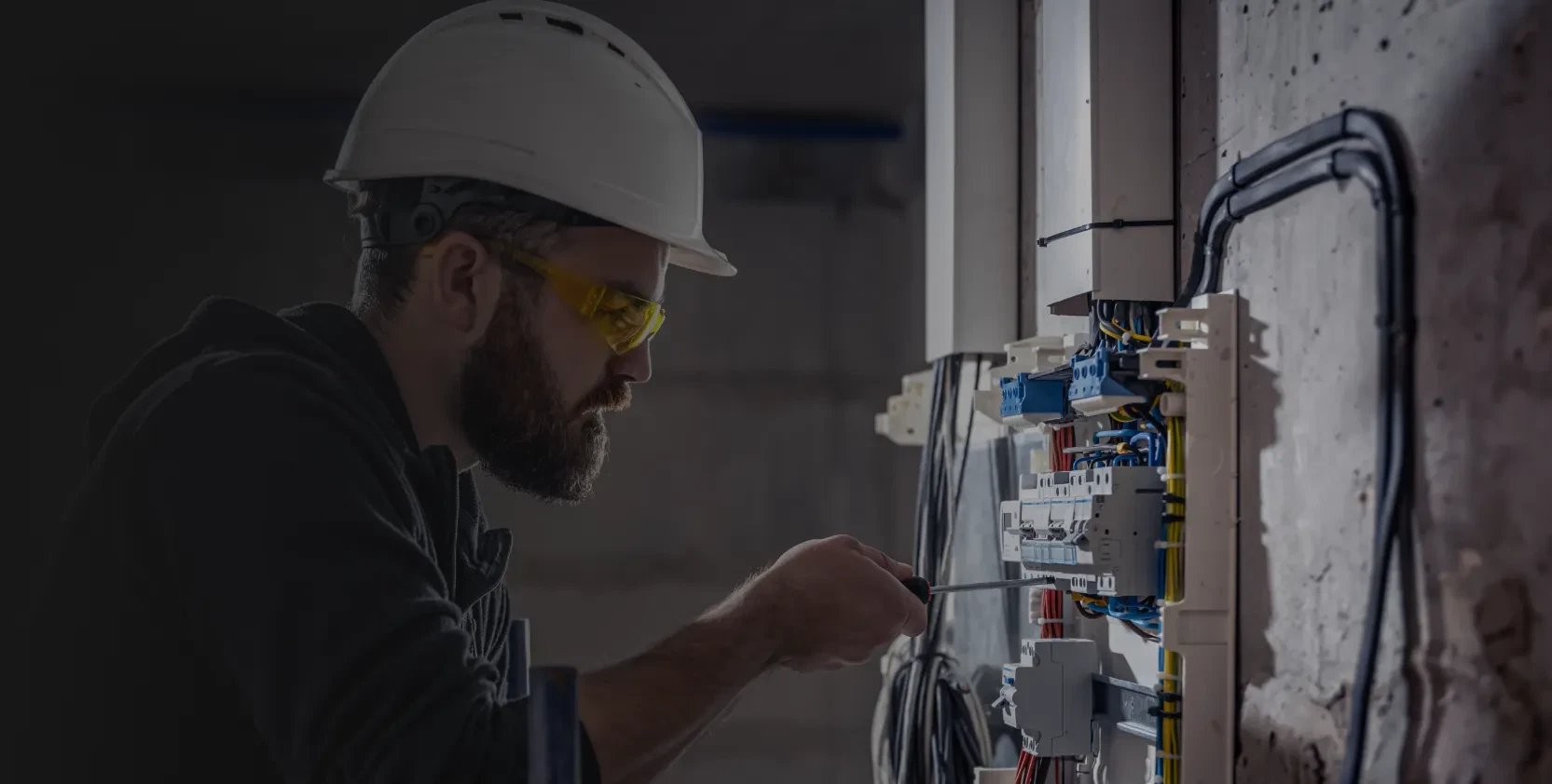 Facility maintenance is under process by a technician as he repairs the switchboard.